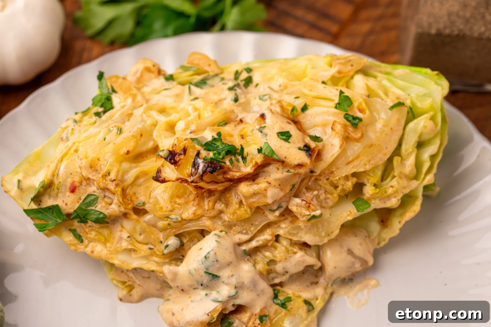 Creamy Garlic Parmesan Cabbage wedge on a white plate up close to show texture 