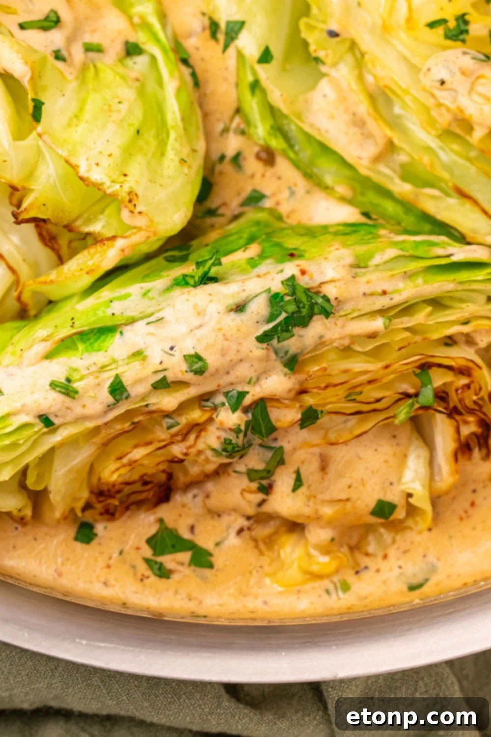 Creamy Garlic Parmesan Cabbage in a skillet coated with sauce and parsley 