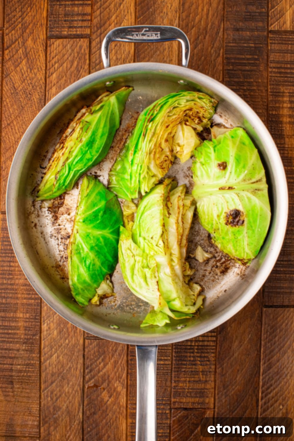 cabbage wedges being sauted in a skillet on table
