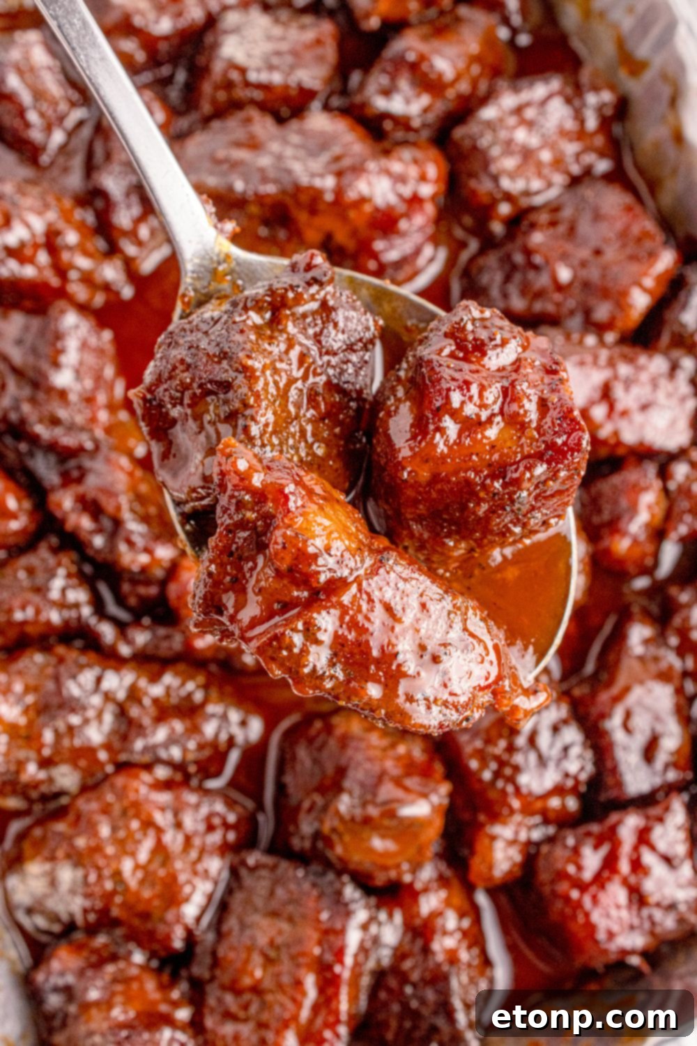 Chuck Roast Burnt Ends in a pan with a spoon scooping some up