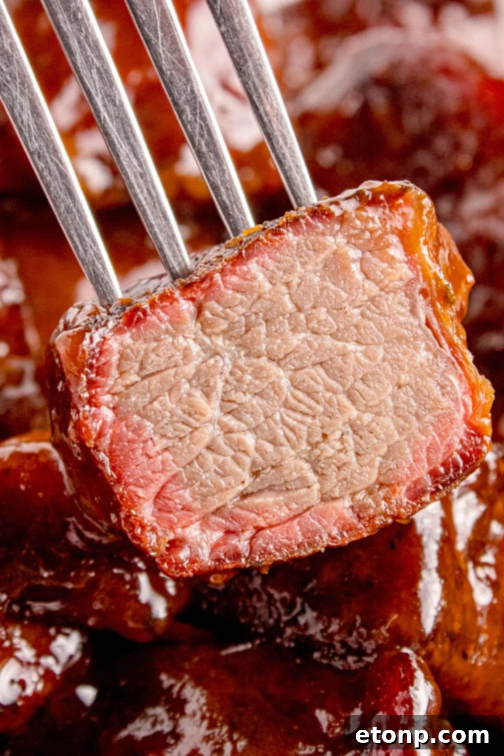 fork with a piece of burnt end that is cut in half to show the meat on it