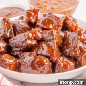 Chuck Roast Burnt Ends in a bowl sitting on table with sauce and beans in background