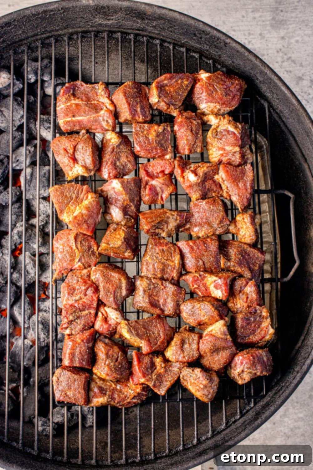 charcoal grill with pieces of steak spread out over it