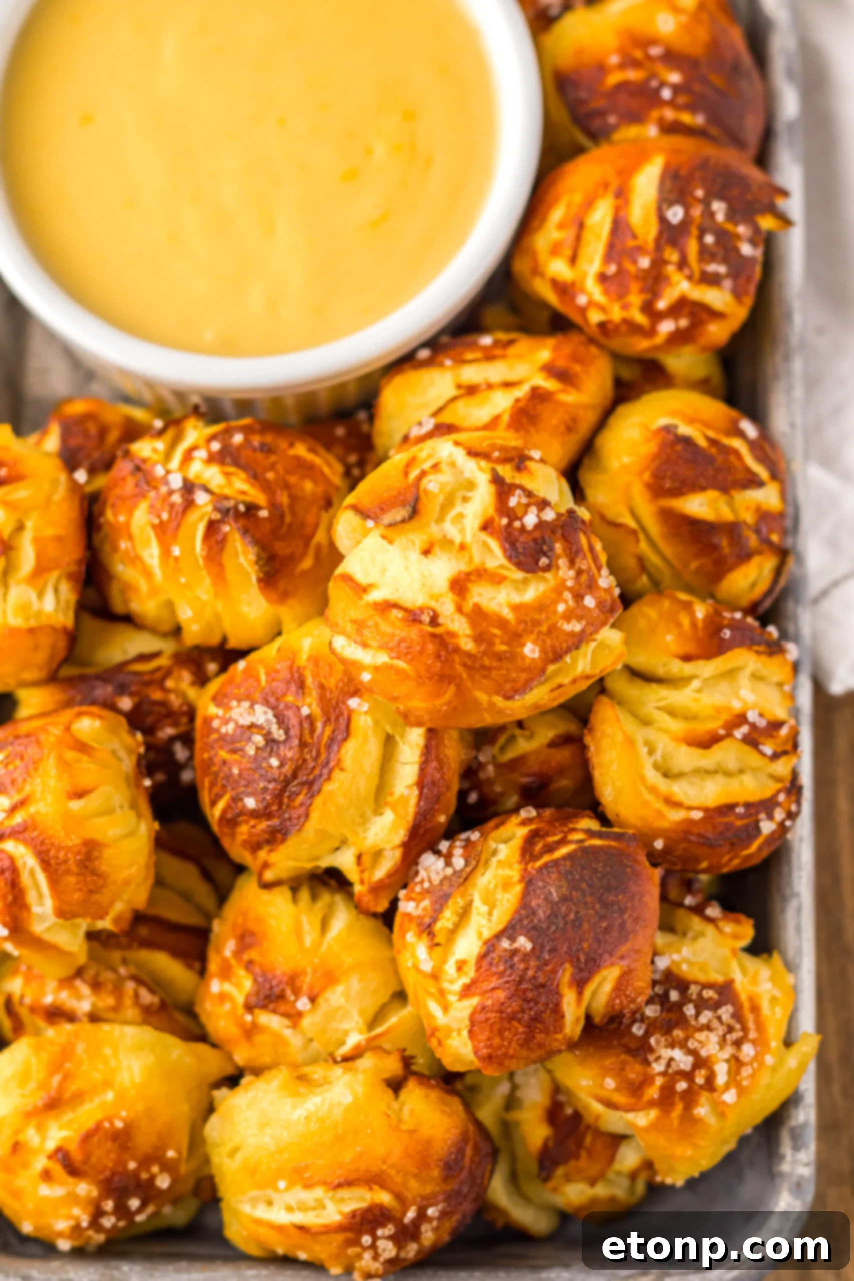 Easy Biscuit Pretzel Bites with Cheese Sauce on a tray sitting on table with a glass to the side