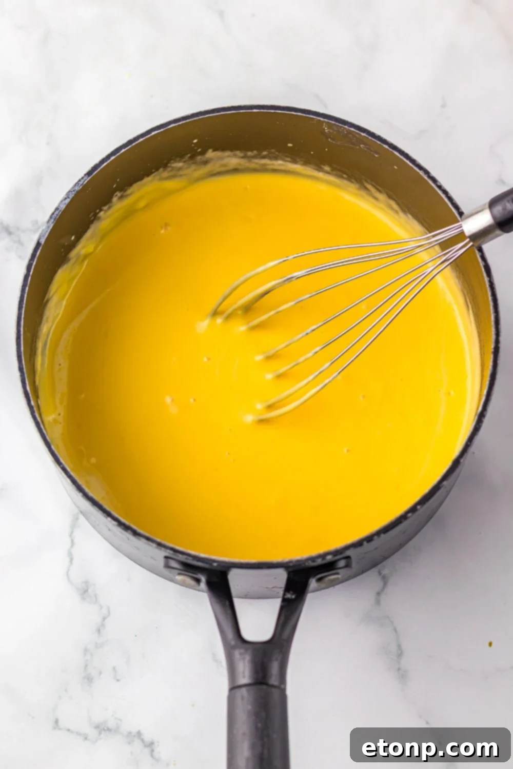 cheese sauce in a sauce pan with a whisk
