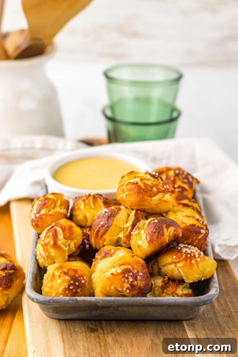 Easy Biscuit Pretzel Bites with Cheese Sauce on table with a towel and glass behind it on table