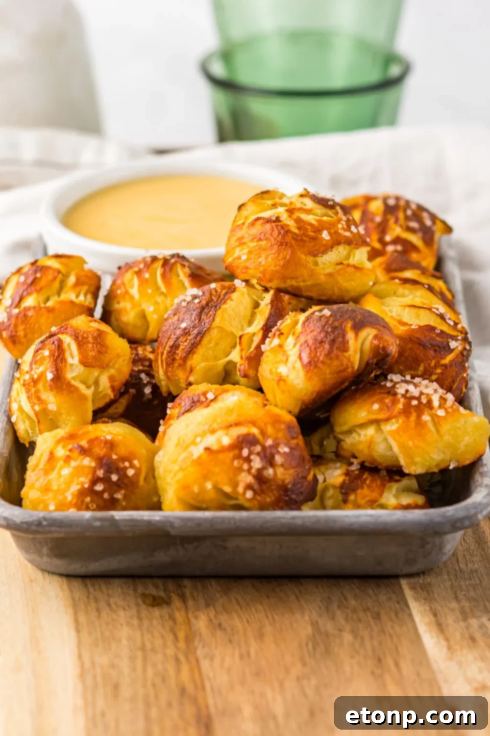 Easy Biscuit Pretzel Bites with Cheese Sauce sitting on tray with a green glass to side