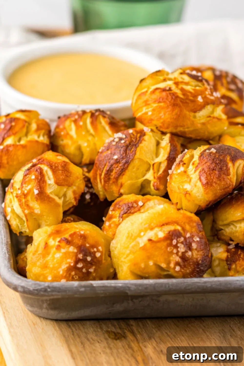 Easy Biscuit Pretzel Bites with Cheese Sauce in a pan with a close up view of it on table