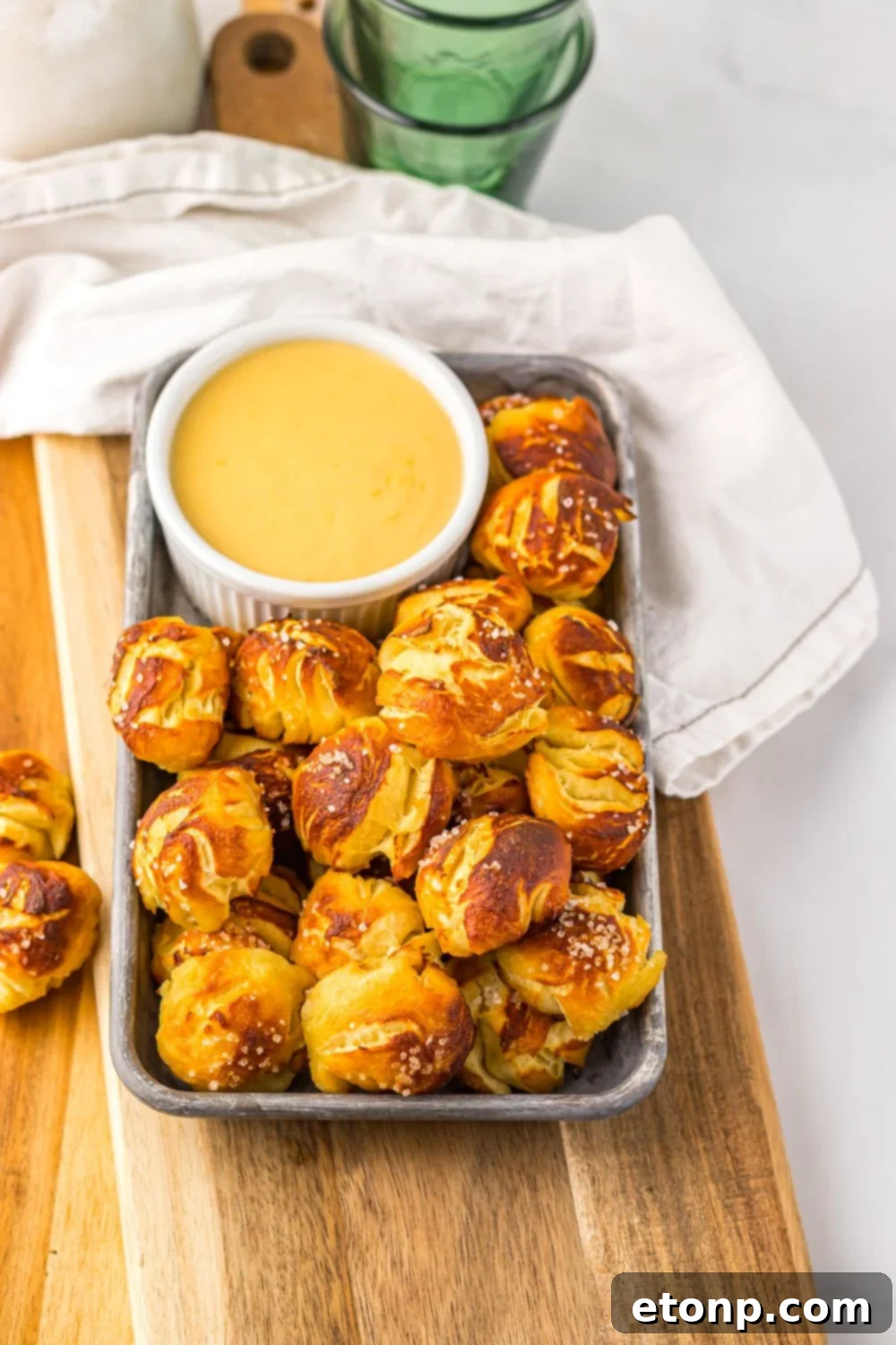Easy Biscuit Pretzel Bites with Cheese Sauce on a tray sitting on table with a towel to side