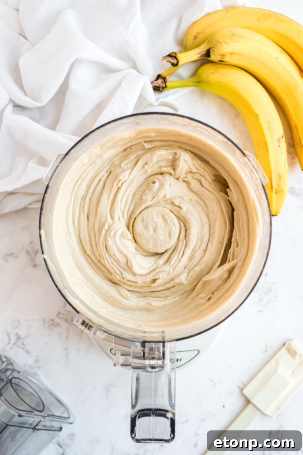 Effortless One-Ingredient Banana Ice Cream 11 Banana Ice Cream in a food processor all mixed up with bananas to side