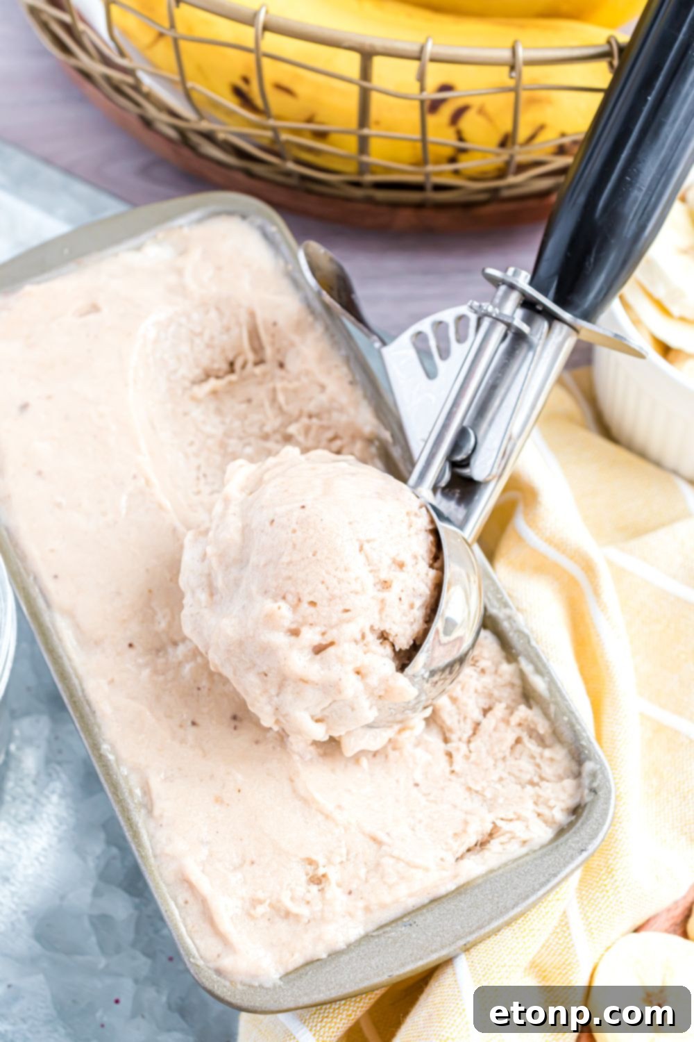Effortless One-Ingredient Banana Ice Cream 16 loaf pan with Banana Ice Cream in it and a scoop full of ice cream