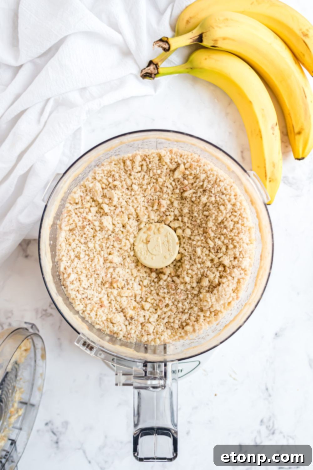 Effortless One-Ingredient Banana Ice Cream 9 Banana Ice Cream being made in a food processor with a bundle of bananas to side