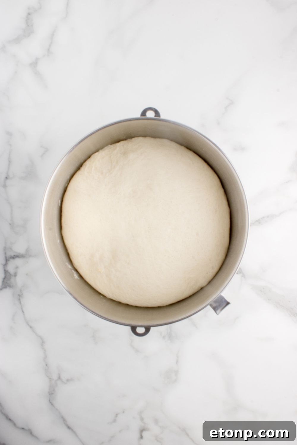 risen dough in a metal bowl on table 