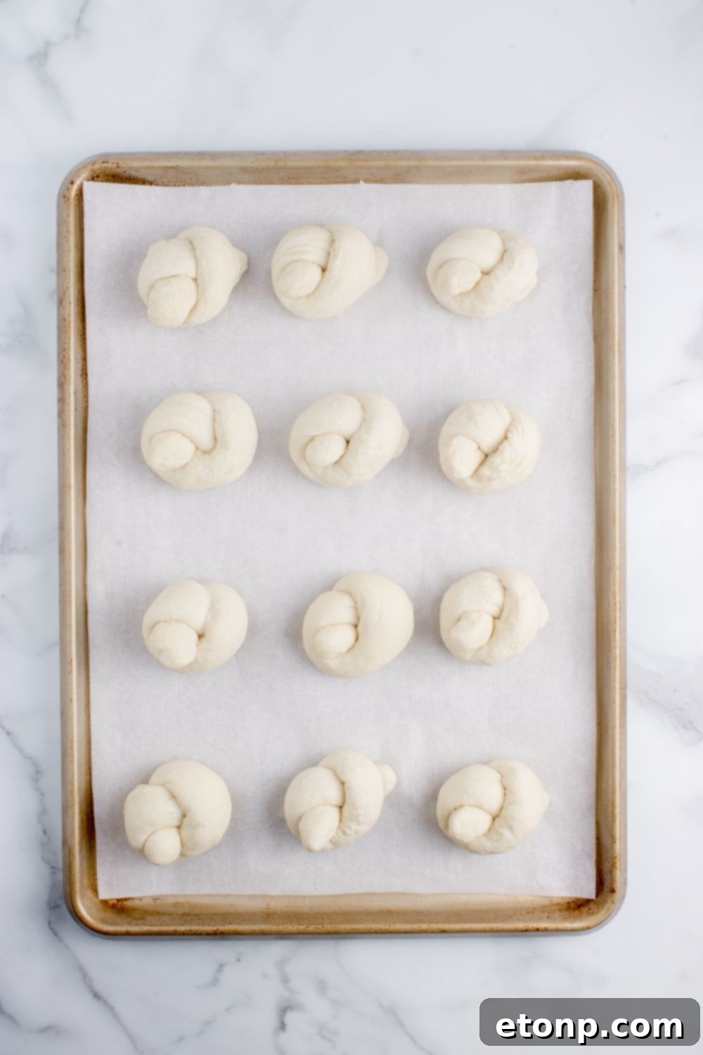 rolled garlic knots on a baking sheet on table 