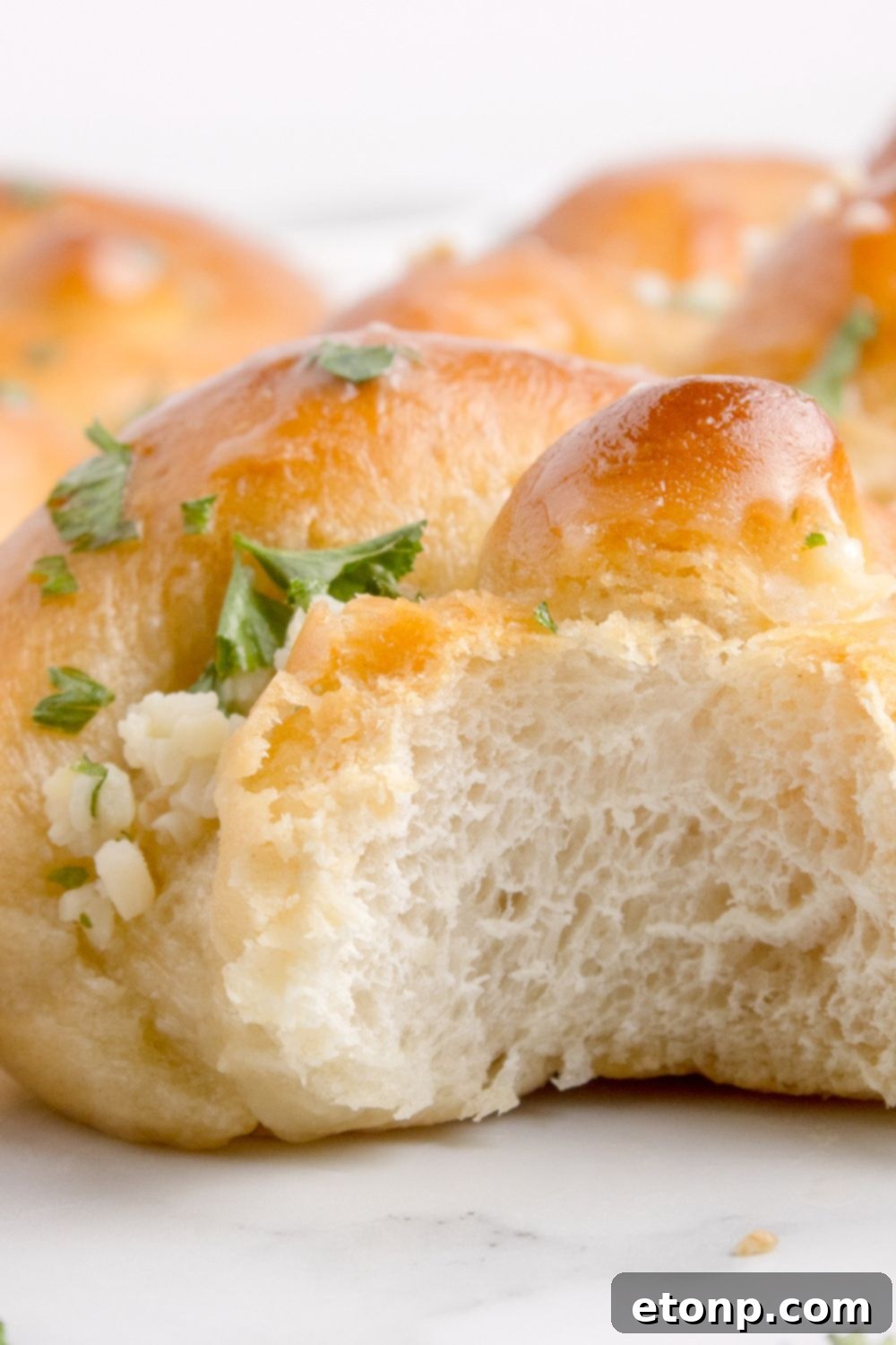 Homemade Garlic Knot sitting on table with a bite taken out of it 