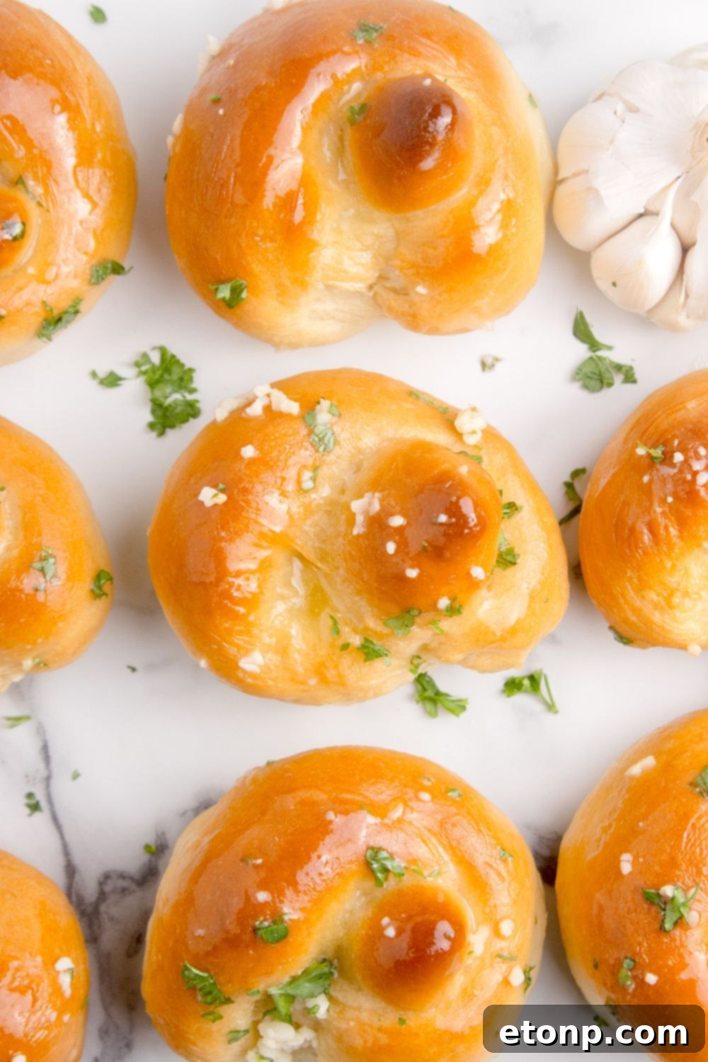 Homemade Garlic Knots spread out on table all brushed with butter and parsley