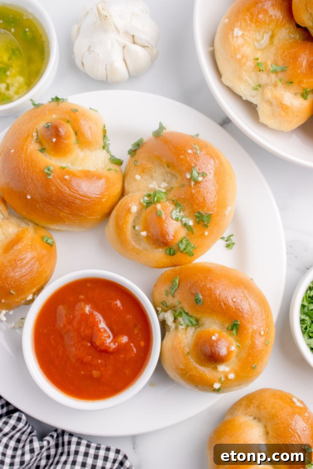 Homemade Garlic Knots on a plate with a bowl of marinara on side and garlic butter 