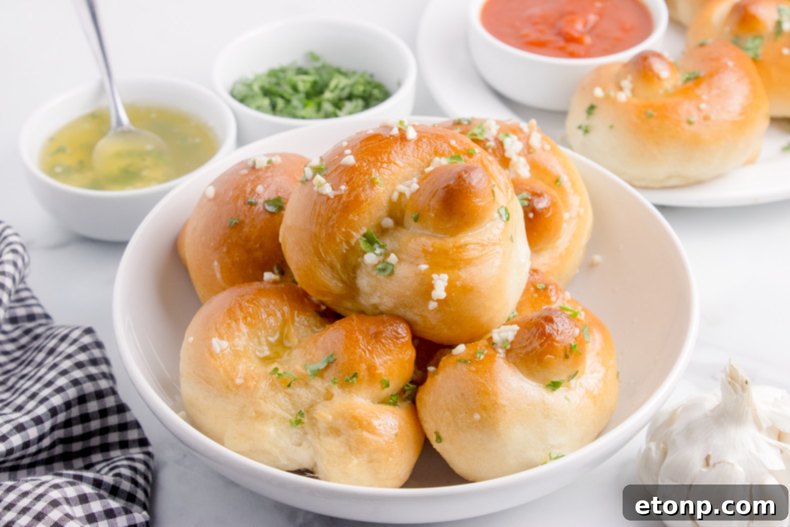 Homemade Garlic Knots on a plate with a bowl of marinara on side and garlic butter 