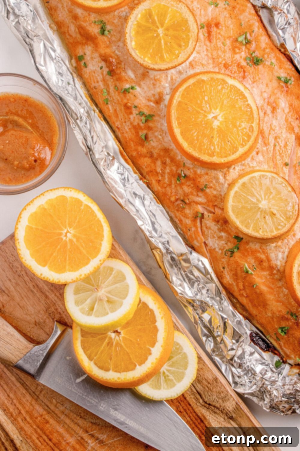 Simple Grilled Honey Mustard Salmon Foil Packets 17 Grilled Honey Mustard Salmon in Foil sitting on table, with more oranges sliced and placed on cutting board to side