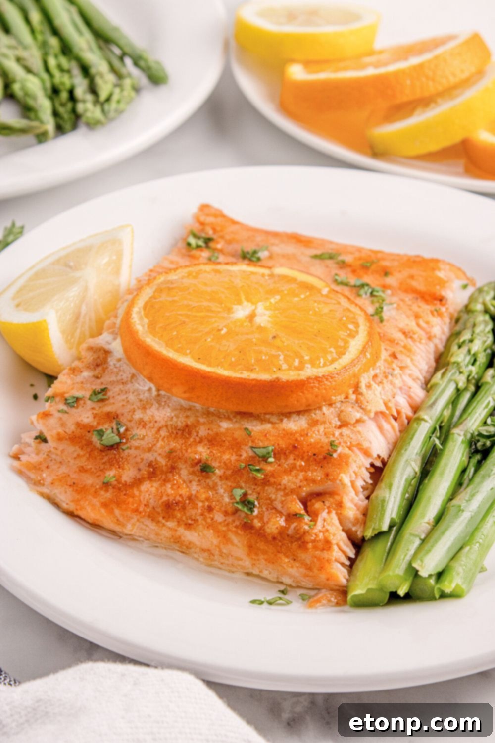 Simple Grilled Honey Mustard Salmon Foil Packets 21 side view of table with a plate of Grilled Honey Mustard Salmon, a side of asparagus, and lemon wedge to side
