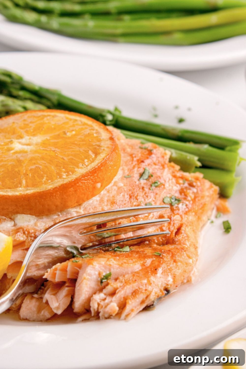 Simple Grilled Honey Mustard Salmon Foil Packets 23 Grilled Honey Mustard Salmon on plate with a fork cutting into salmon with asparagus tose side and on a second plate