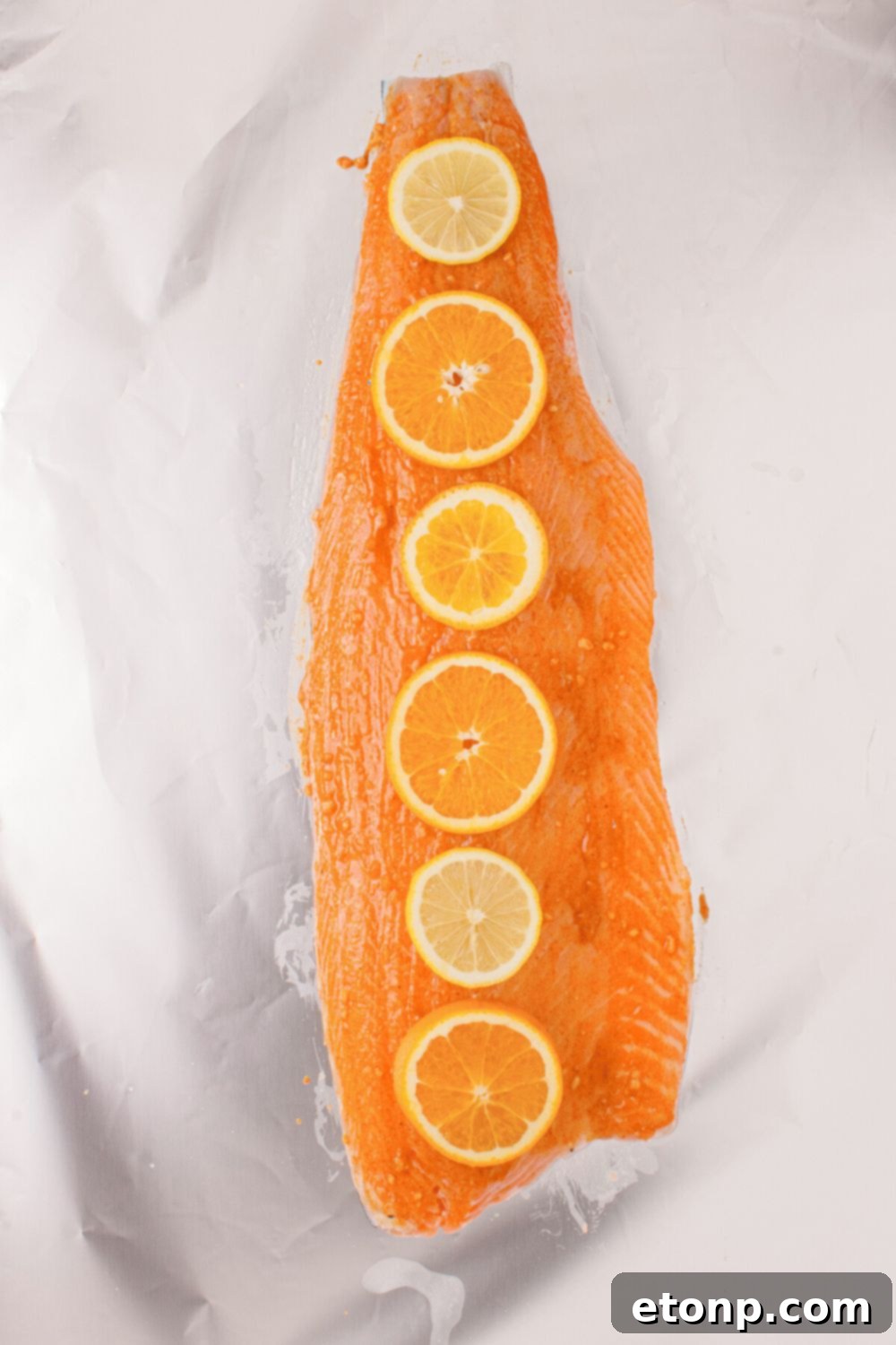 Simple Grilled Honey Mustard Salmon Foil Packets 9 raw salmon with sauce spread on top and orange slices
