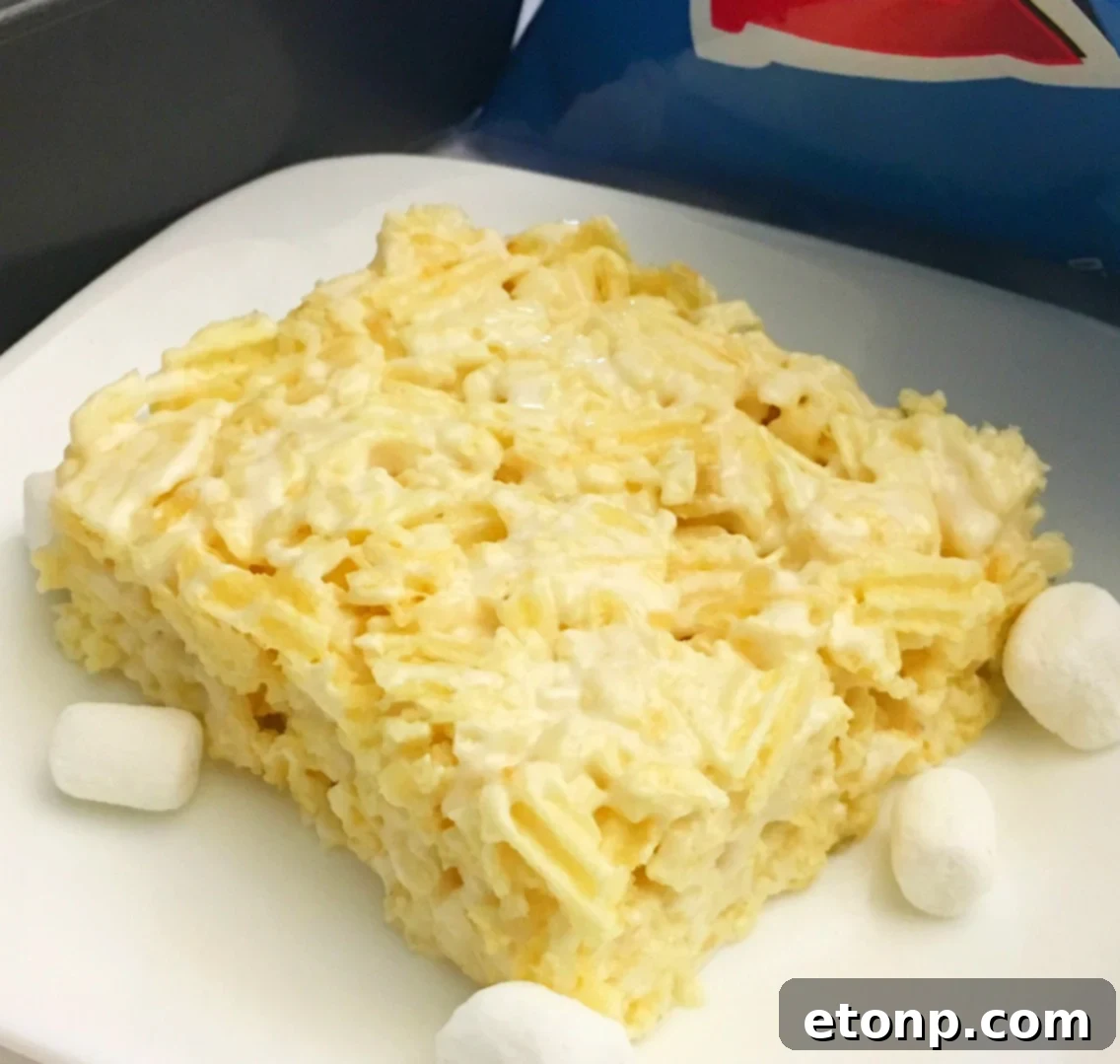 Close-up of golden brown Ruffles Krispie Treats in a baking pan, showing the crunchy texture and sweet marshmallow coating.