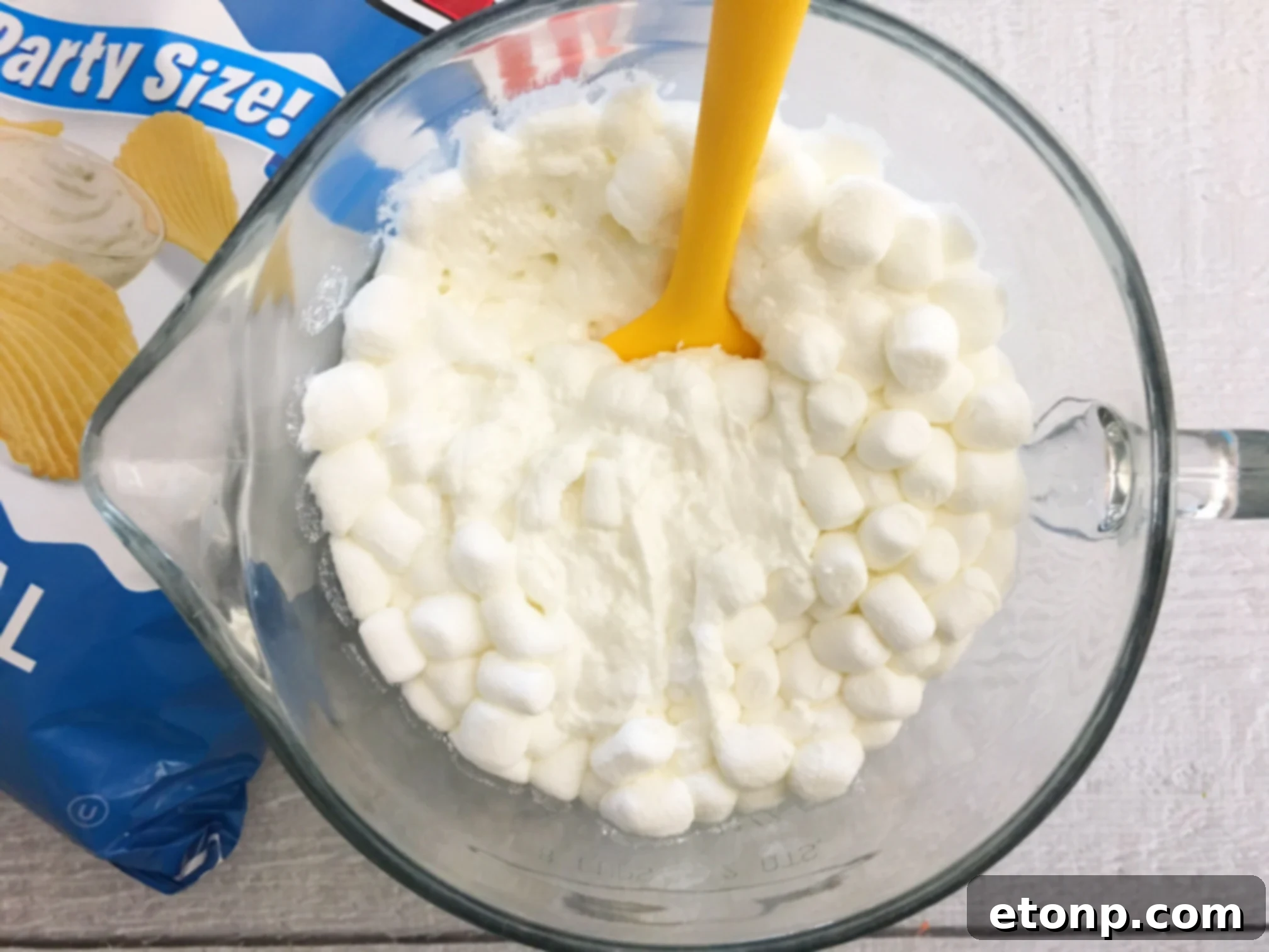 Hand reaching for a Ruffles Krispie Treat from a bowl, highlighting the enticing and easy-to-grab nature of the snack.