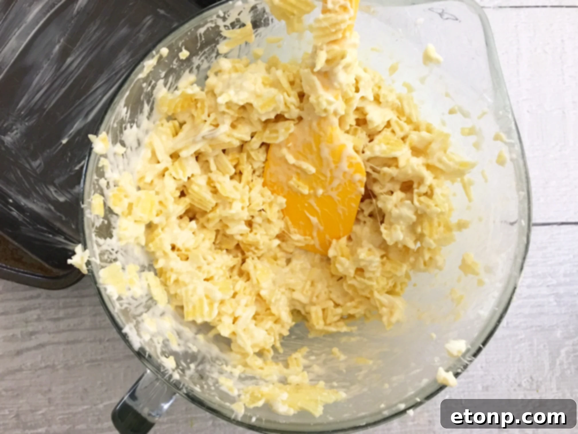 Ruffles Krispie Treats being pressed down into a baking pan, illustrating the simple assembly process.