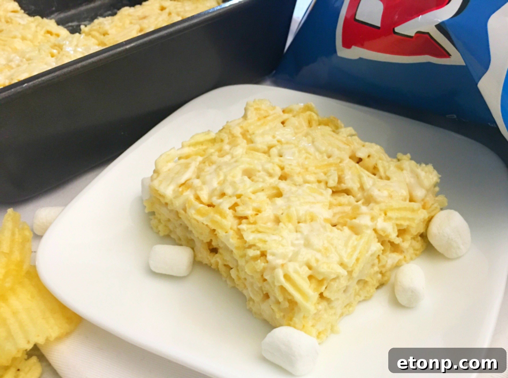 Spatula pressing the Ruffles Krispie Treat mixture into a baking pan, ensuring an even layer.