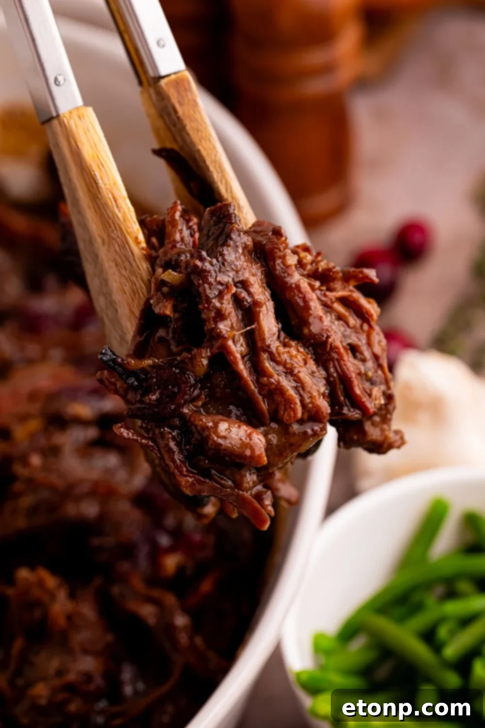 tongs with some shredded cranberry roast in it