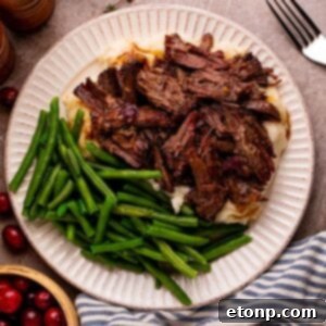 Cranberry Pot Roast on plate with mashed potatoes and fresh green beans and a fork to side on table