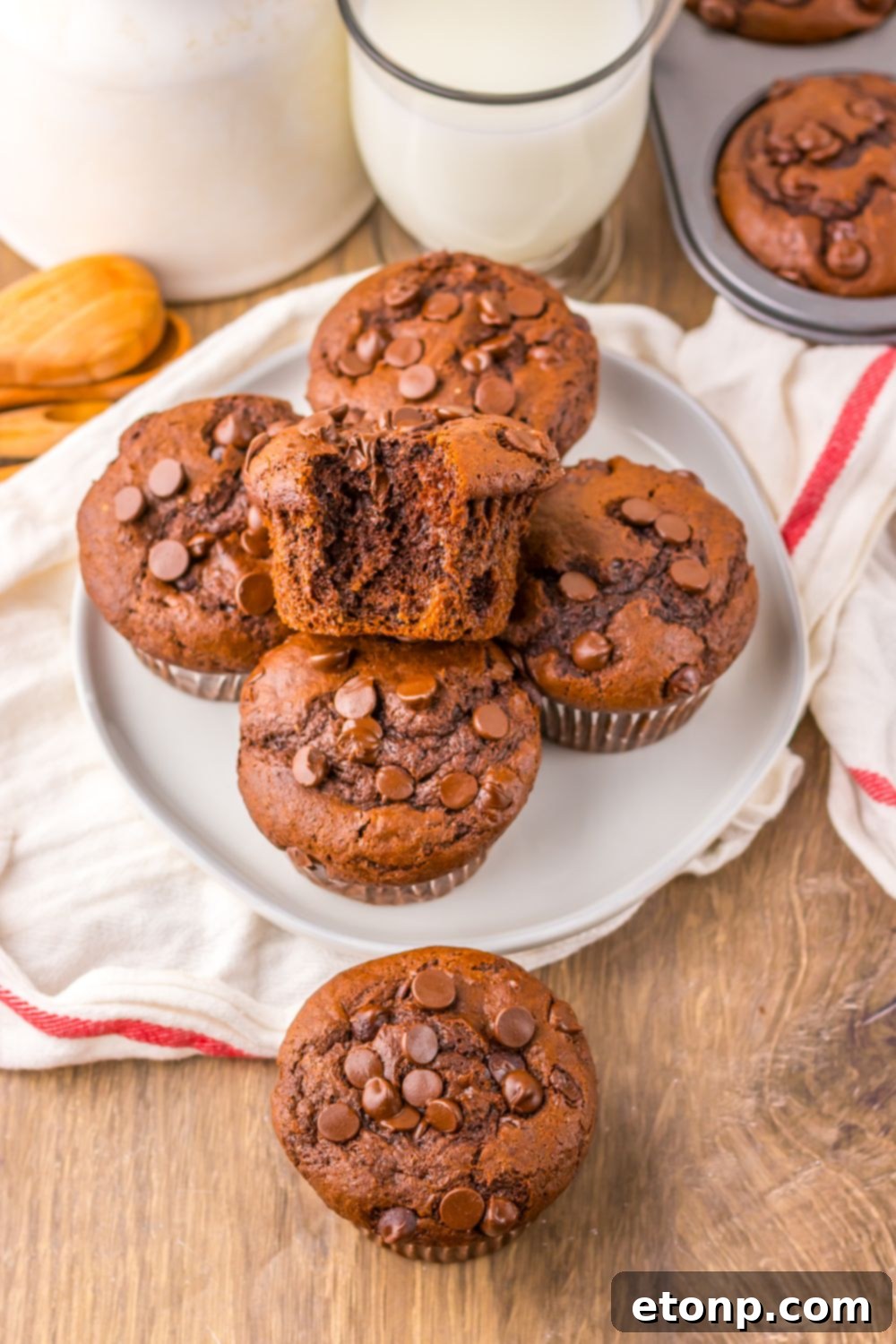 Costco Double Chocolate Muffins Bakery Style Jumbo Rich Moist 13 A freshly baked Costco Double Chocolate Muffin on a plate with a glass of milk in the background.