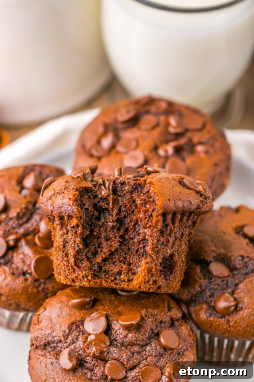 Costco Double Chocolate Muffins Bakery Style Jumbo Rich Moist 21 Homemade Costco Double Chocolate Muffins stacked on a plate with a bite taken from the top muffin.