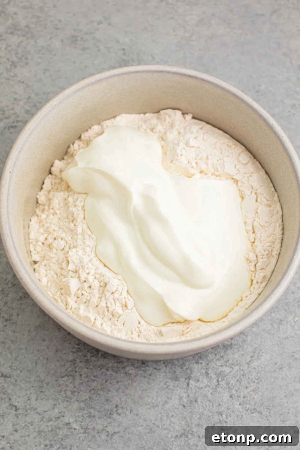 flour and yogurt in a white bowl on table for making 2 Ingredient Dinner Rolls