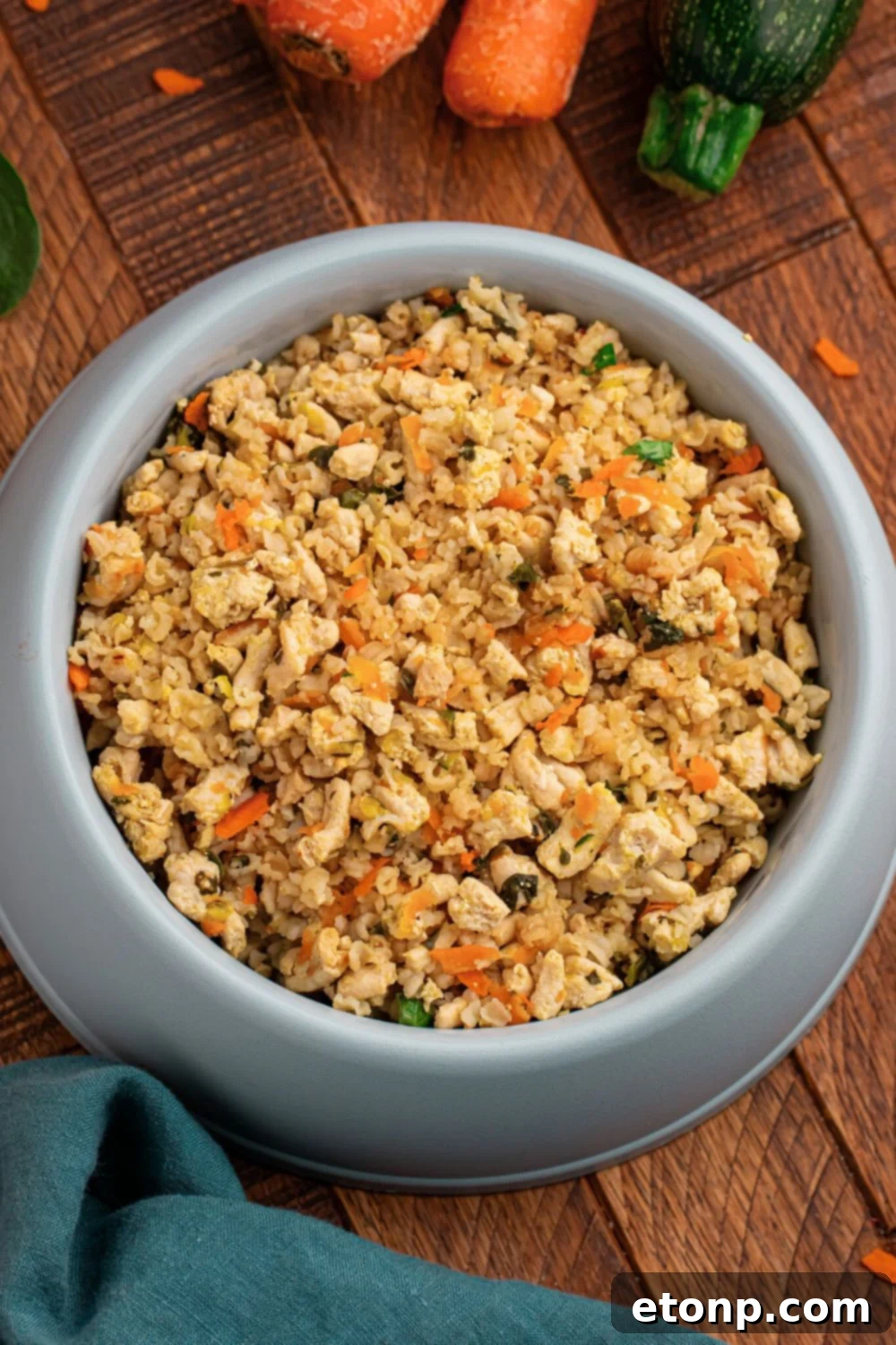 Homemade Turkey and Rice Dog Food with Veggies in a container sitting on table with carrots and zucchini to the side 