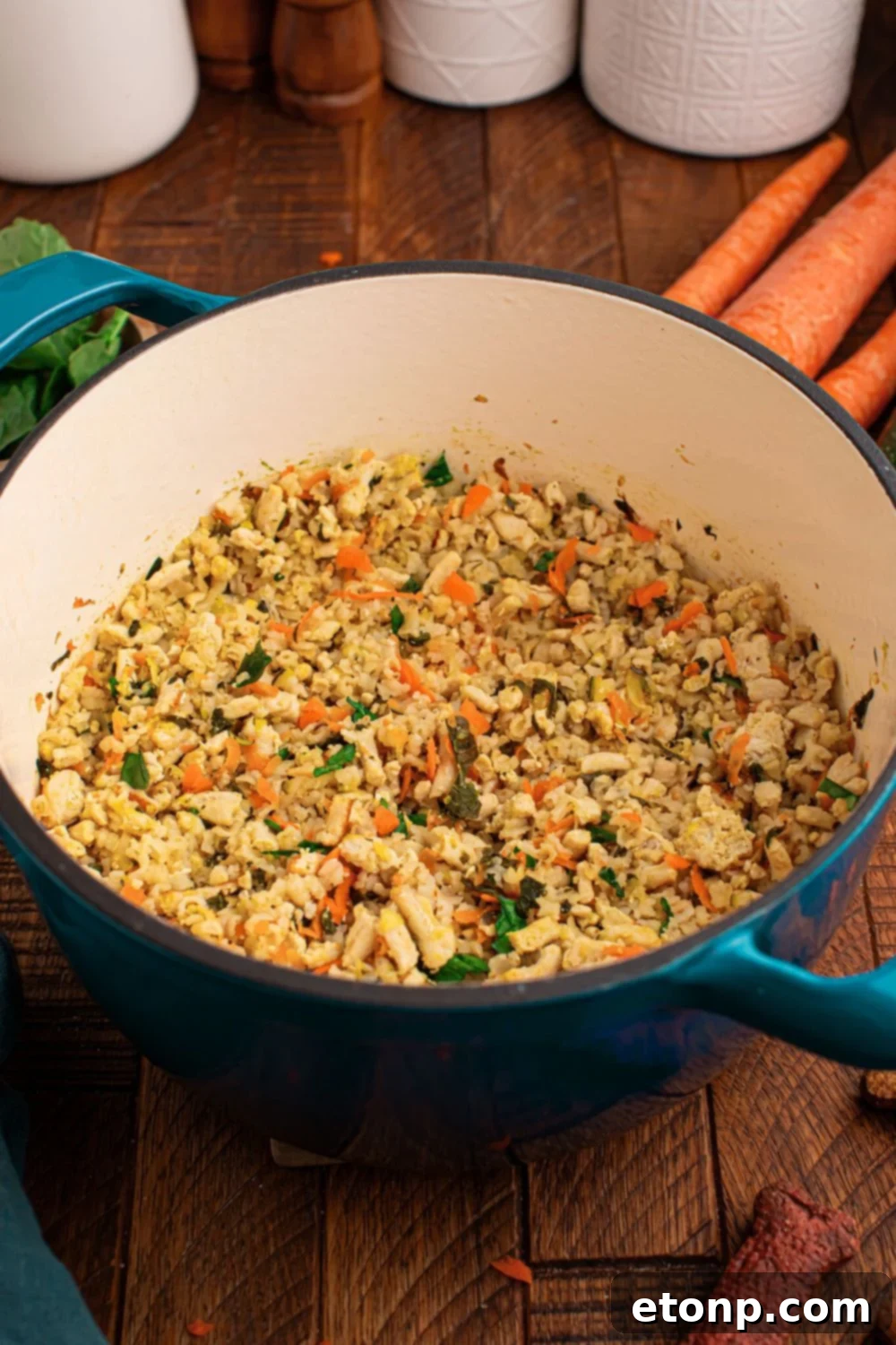 Cooked dog food in a pot sitting on table with carrots and other ingredients around table 