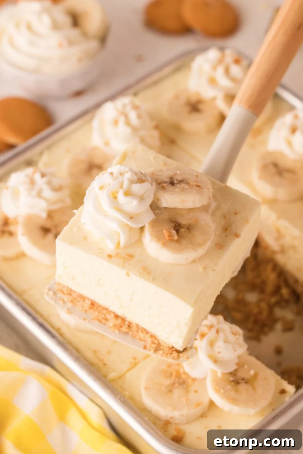 No Bake Banana Pudding Cheesecake Bars in a pan with one being lifted out of the pan with a spatula 