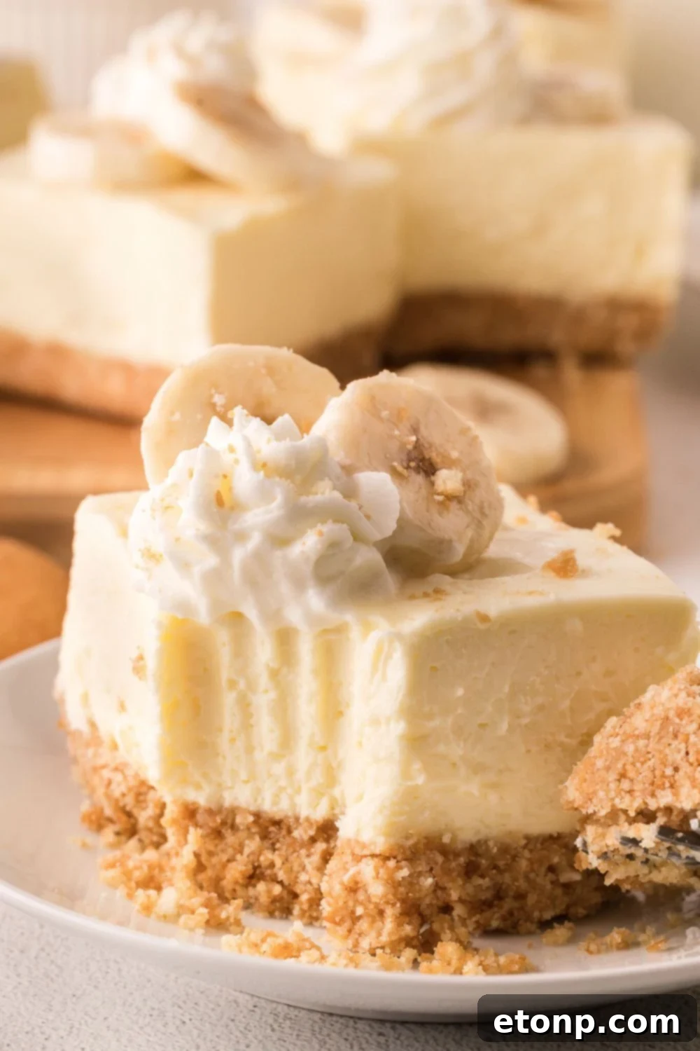 a No Bake Banana Pudding Cheesecake Bar on a plate with one bite taken out of the square 