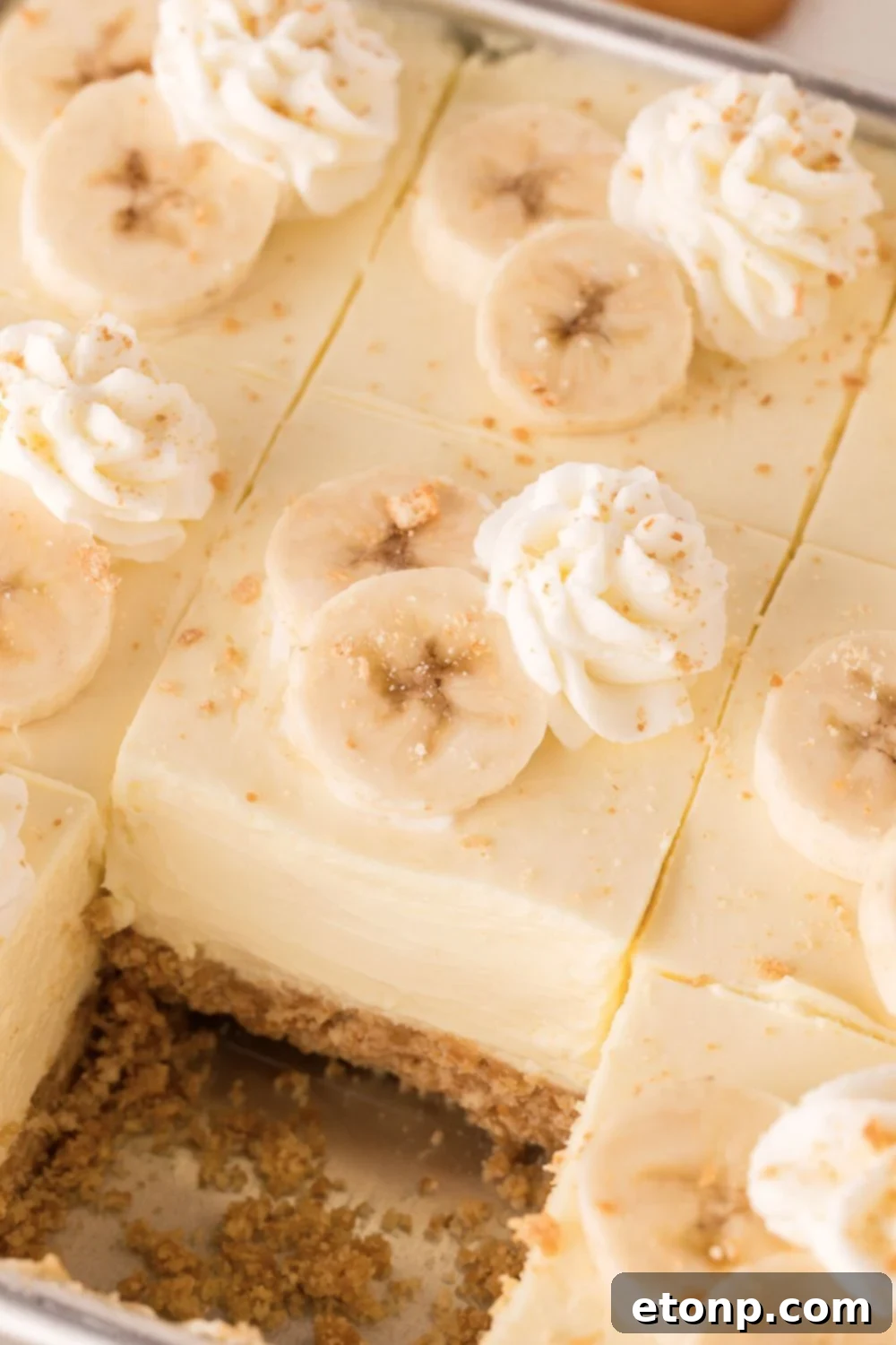 pan on table for No Bake Banana Pudding Cheesecake Bars with one slice taken out of it 