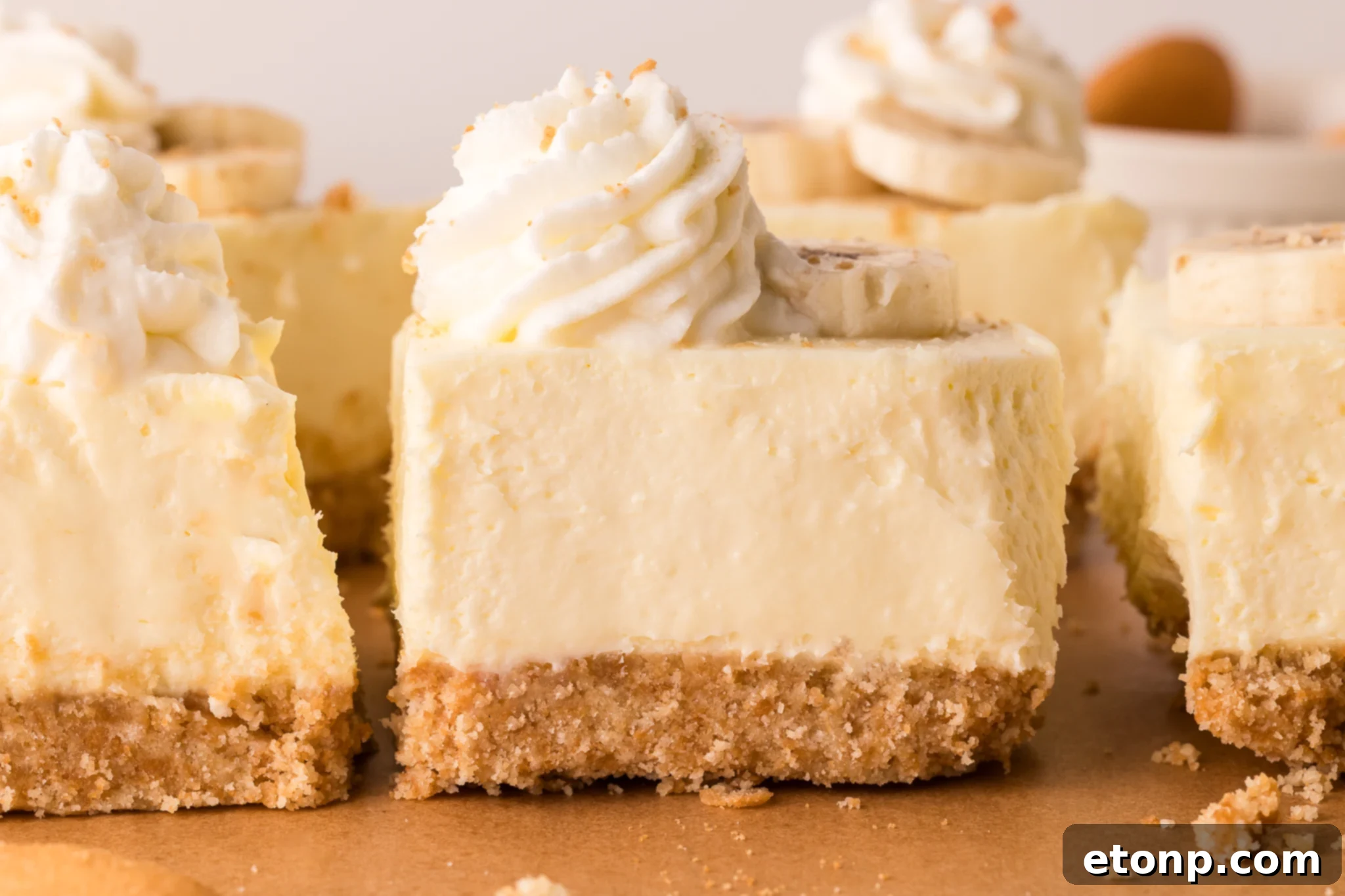 No Bake Banana Pudding Cheesecake Bars lined up on a wooden cutting board 