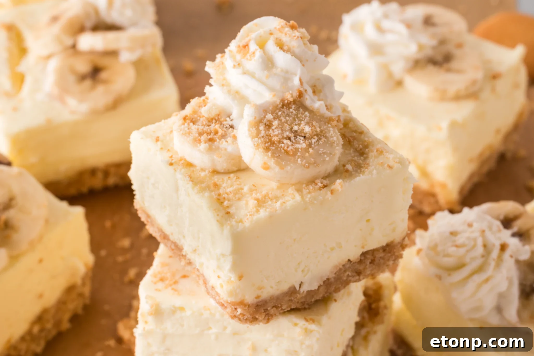 No Bake Banana Pudding Cheesecake Bars stacked on top of one another topped with crumbled vanilla wafers