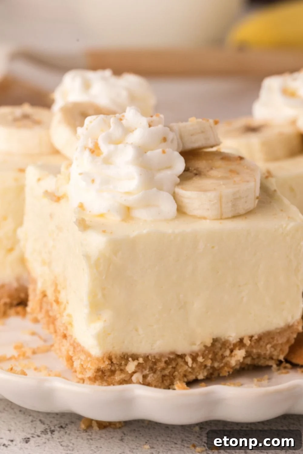 No Bake Banana Pudding Cheesecake Bars sliced and placed on table with crushed cookies around table 