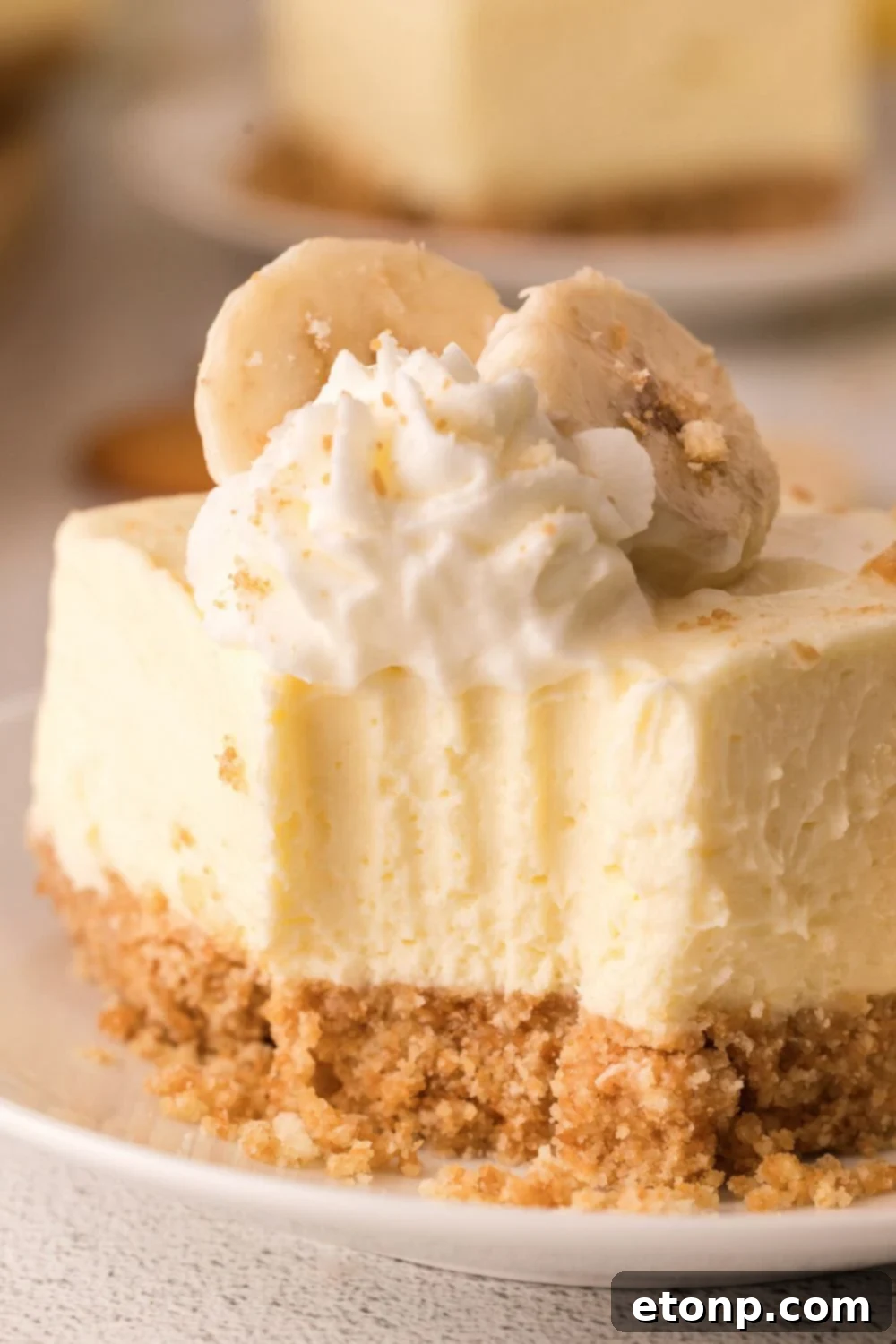 No Bake Banana Pudding Cheesecake Bar on plate with a bite taken out of it 