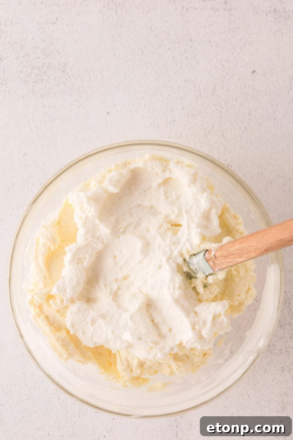 glass bowl with cheesecake batter being mixed in bowl 