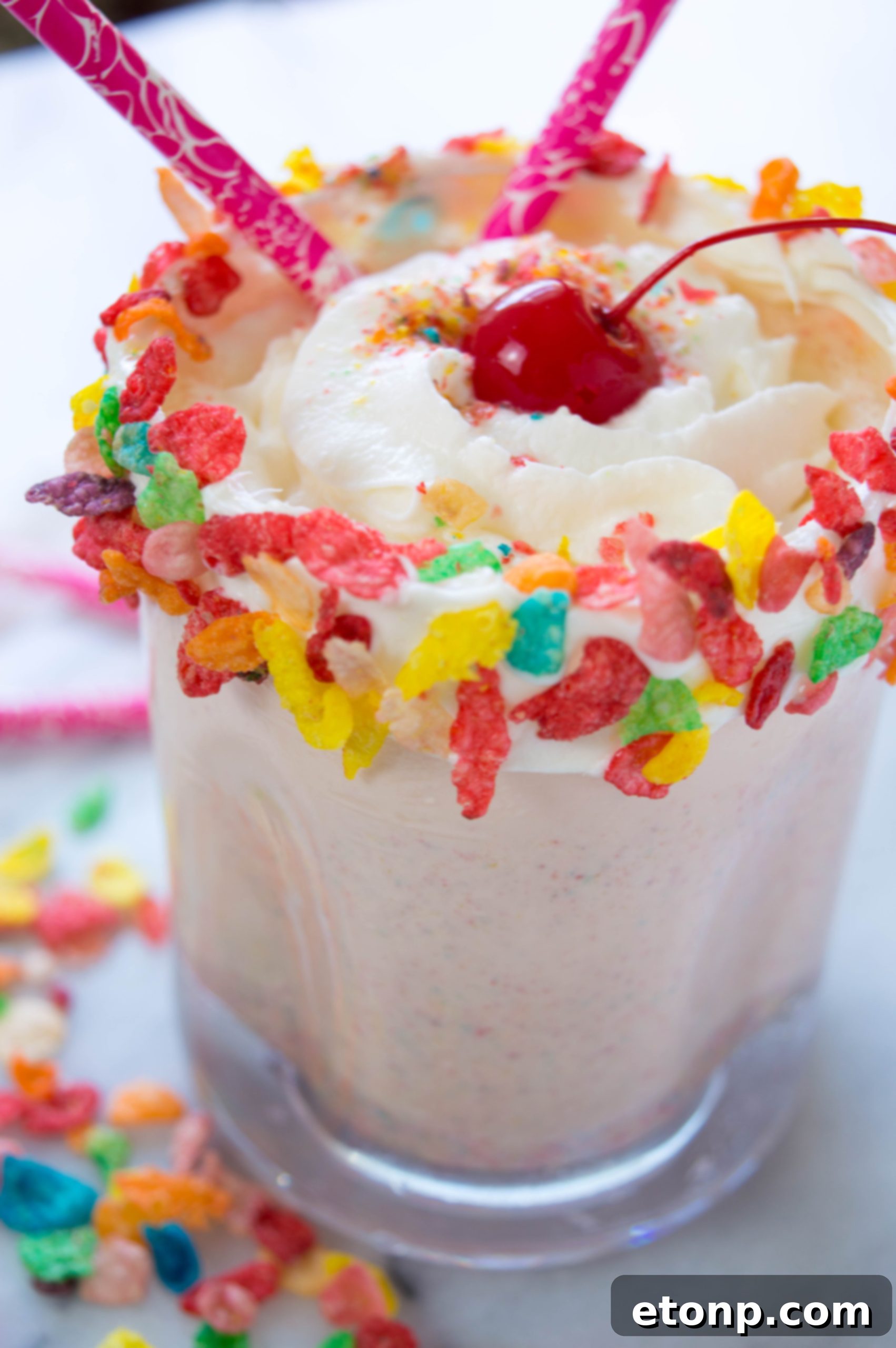 Close-up of a vibrant Fruity Pebbles Milkshake topped with whipped cream and sprinkles