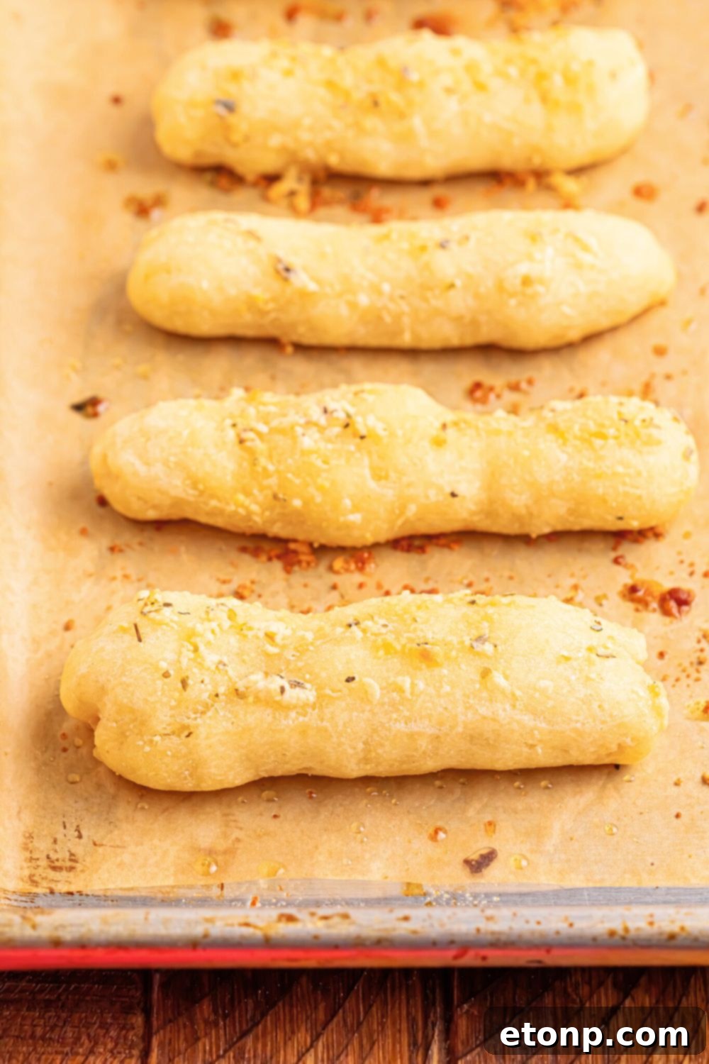 Easy Buttery Garlic Parmesan Breadsticks Two Ingredients 11 A baking tray filled with golden brown, baked 2-Ingredient Garlic Parmesan Breadsticks on parchment paper