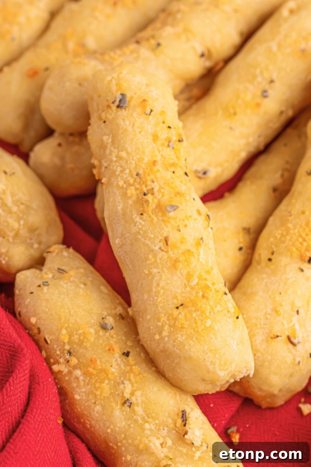 Easy Buttery Garlic Parmesan Breadsticks Two Ingredients 14 A stack of perfectly golden 2-Ingredient Garlic Parmesan Breadsticks piled on top of each other on a wooden table.