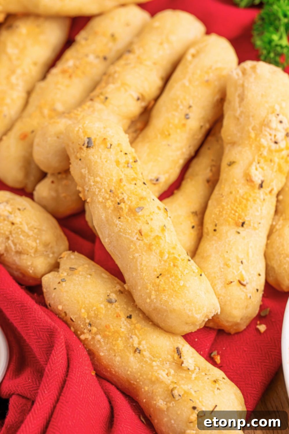 Easy Buttery Garlic Parmesan Breadsticks Two Ingredients 17 An overhead view of a table filled with numerous golden 2-Ingredient Garlic Parmesan Breadsticks, casually scattered.