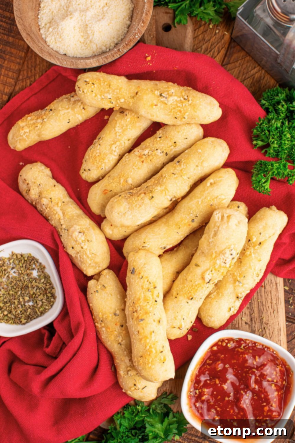 Easy Buttery Garlic Parmesan Breadsticks Two Ingredients 3 Assortment of freshly baked 2-ingredient breadsticks scattered on a rustic wooden table, with dipping sauce and seasoning bowls nearby